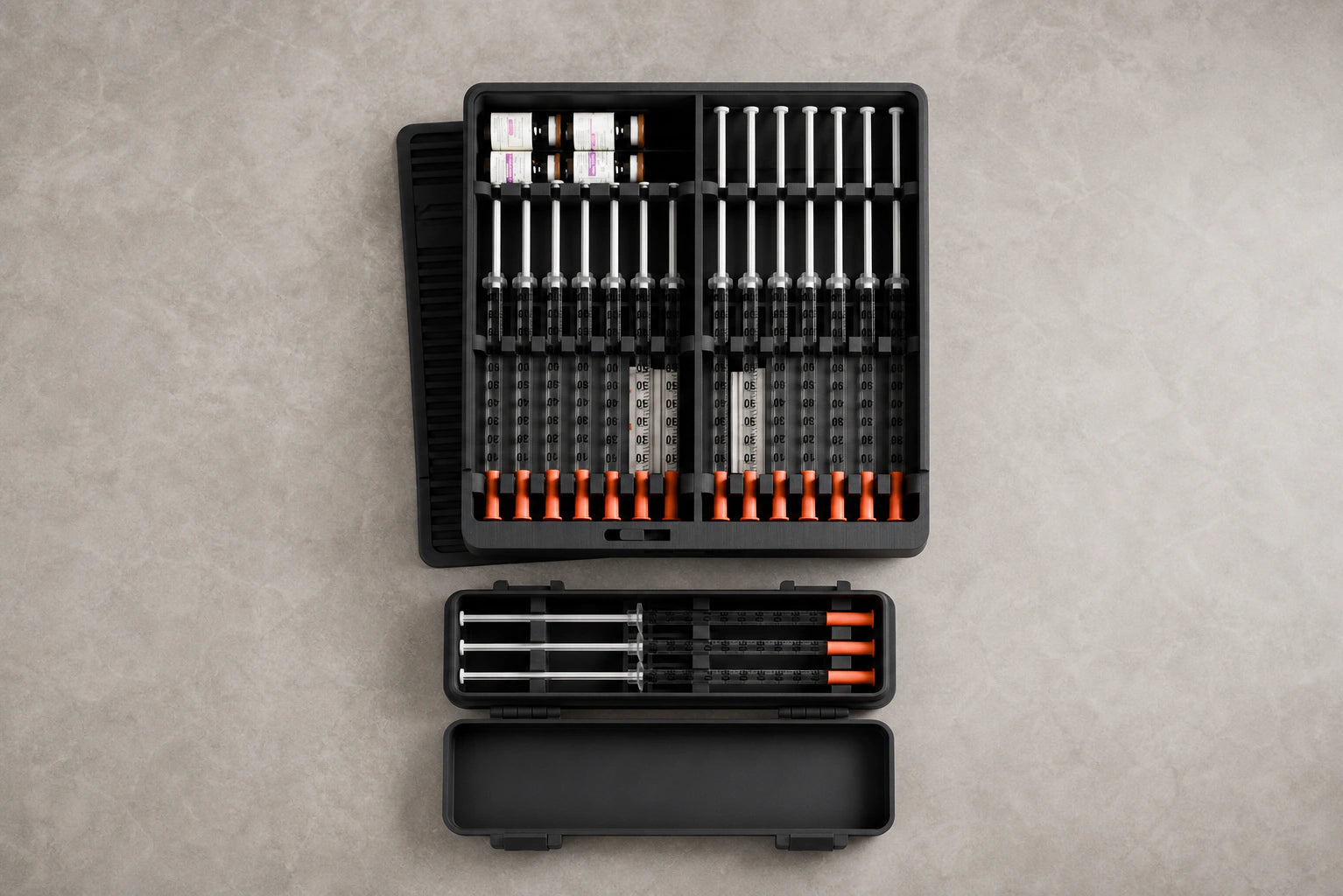Overhead view of the Routine Box arranged with capped demonstration syringes and vials beside the open travel case