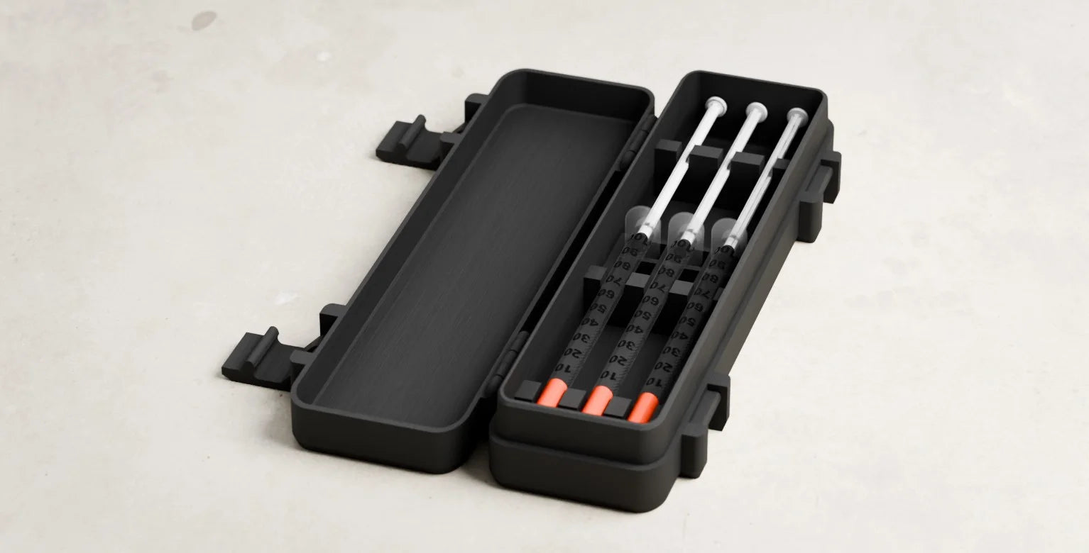 The Routine Box travel case open with three capped syringes inside